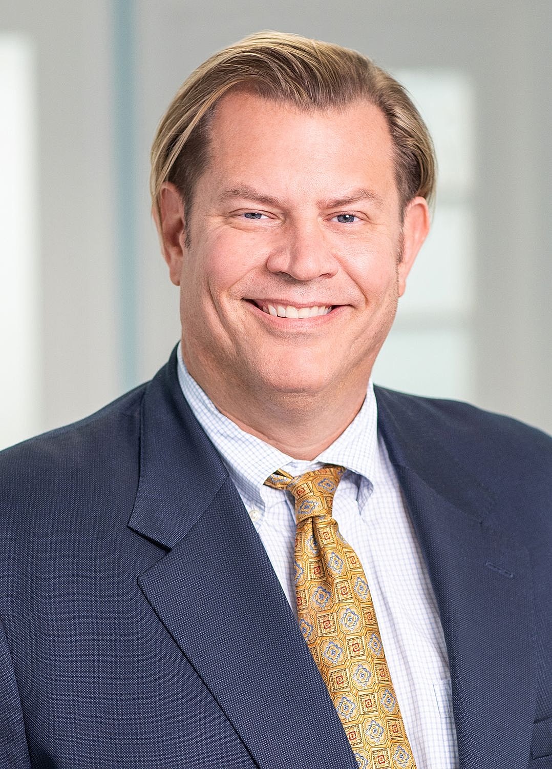 Smiling man in professional attire with tie.