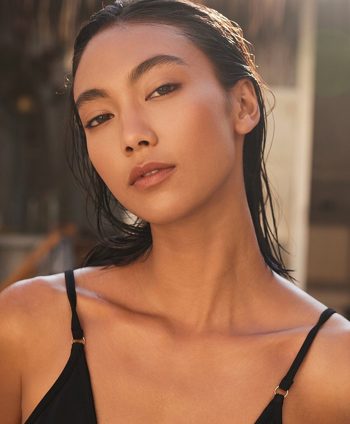 Woman with wet hair sitting on the beach.