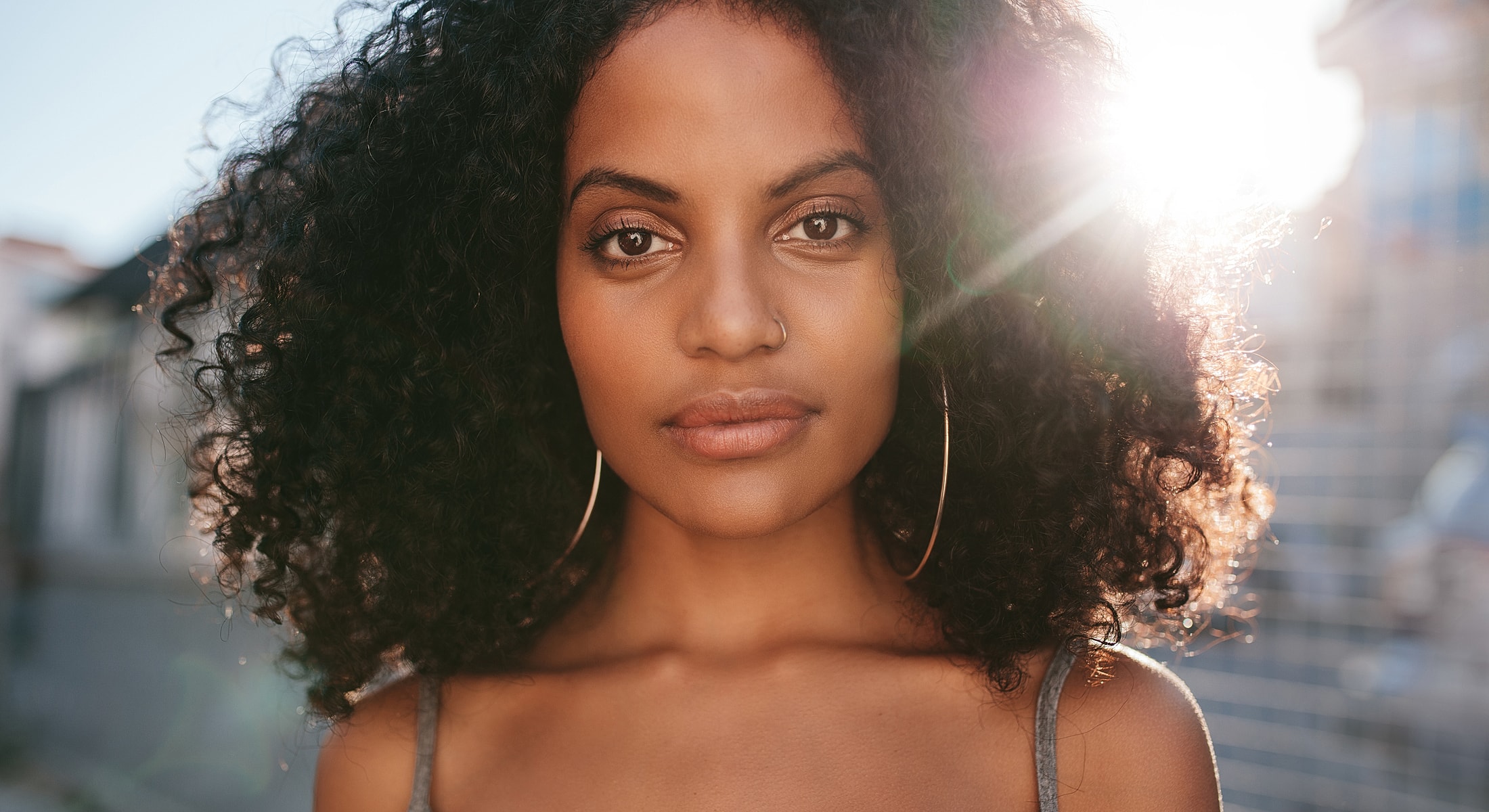 Woman with curly hair against sunlit background.