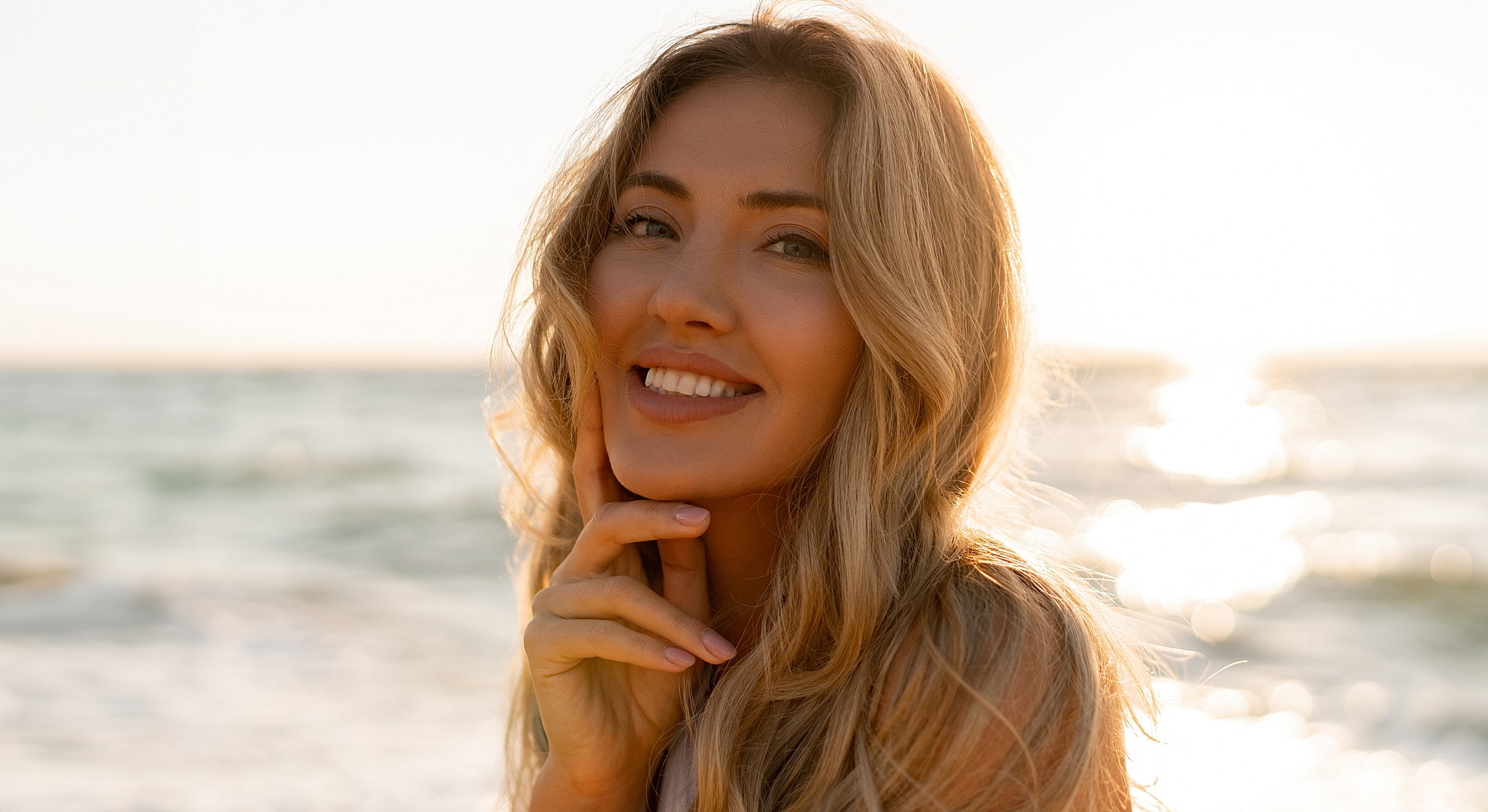 Smiling woman by the beach at sunset.