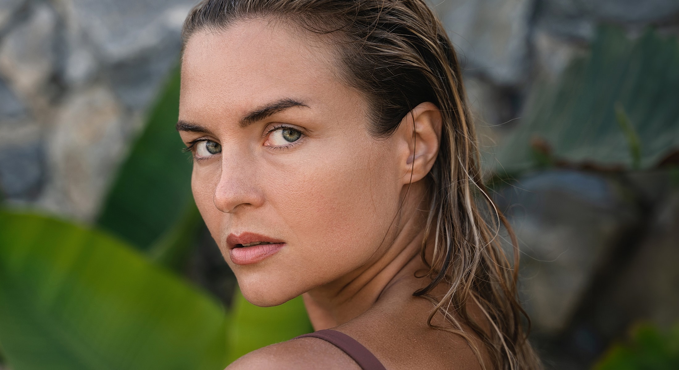 Woman with wet hair against a natural backdrop.