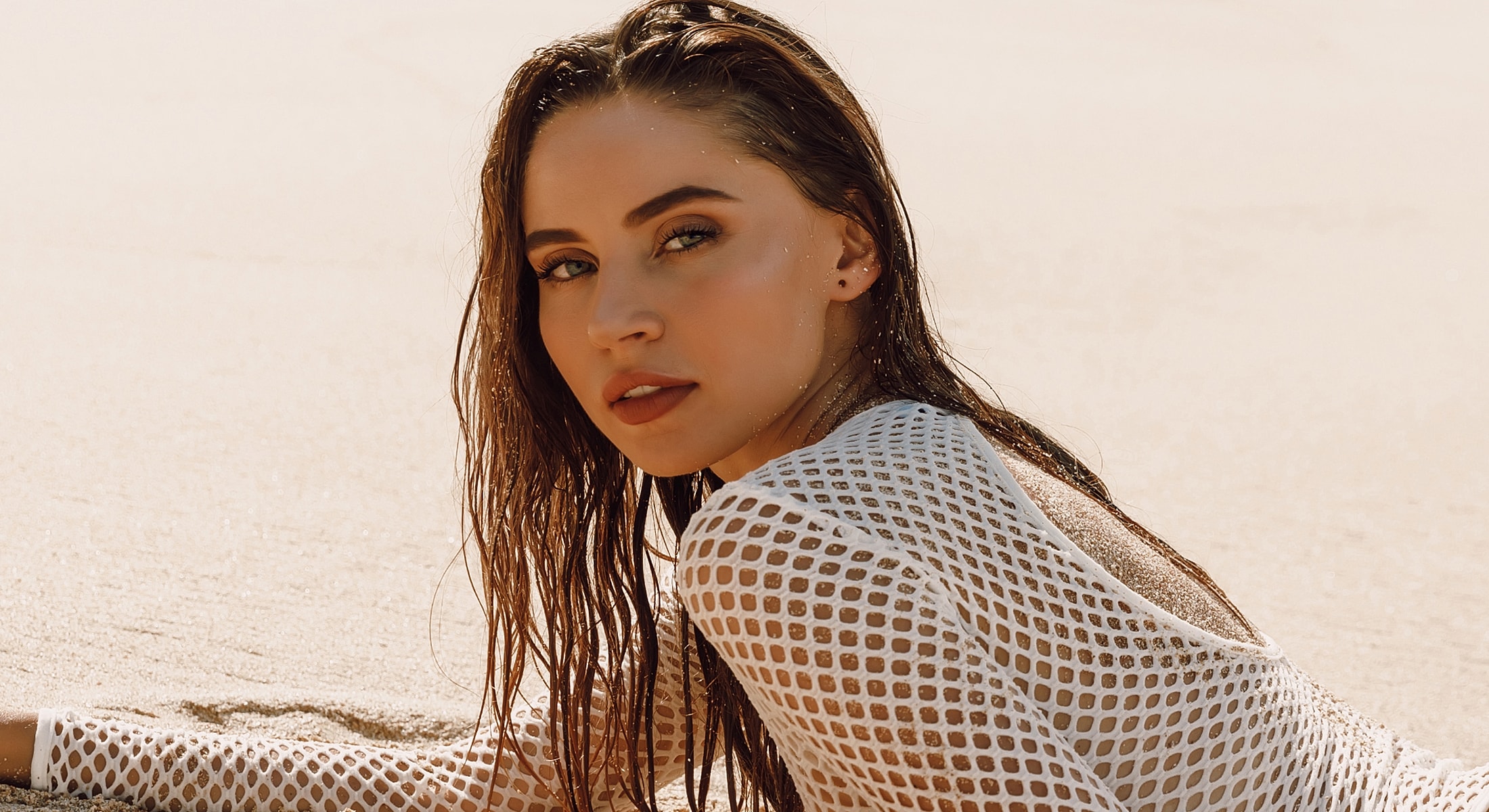 Young woman with wet hair on sandy beach.